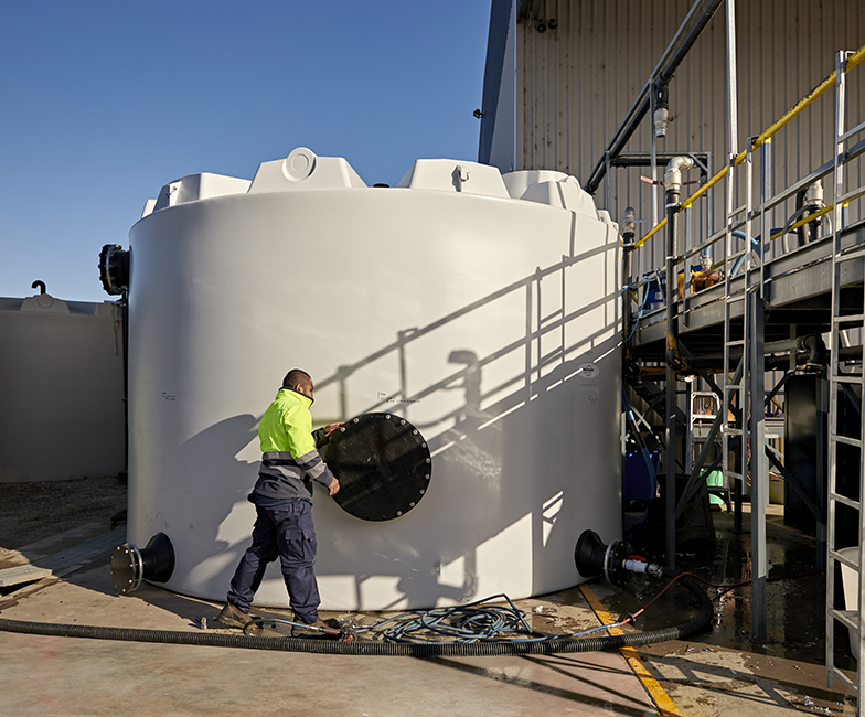 A man is standing next to a large white tank.