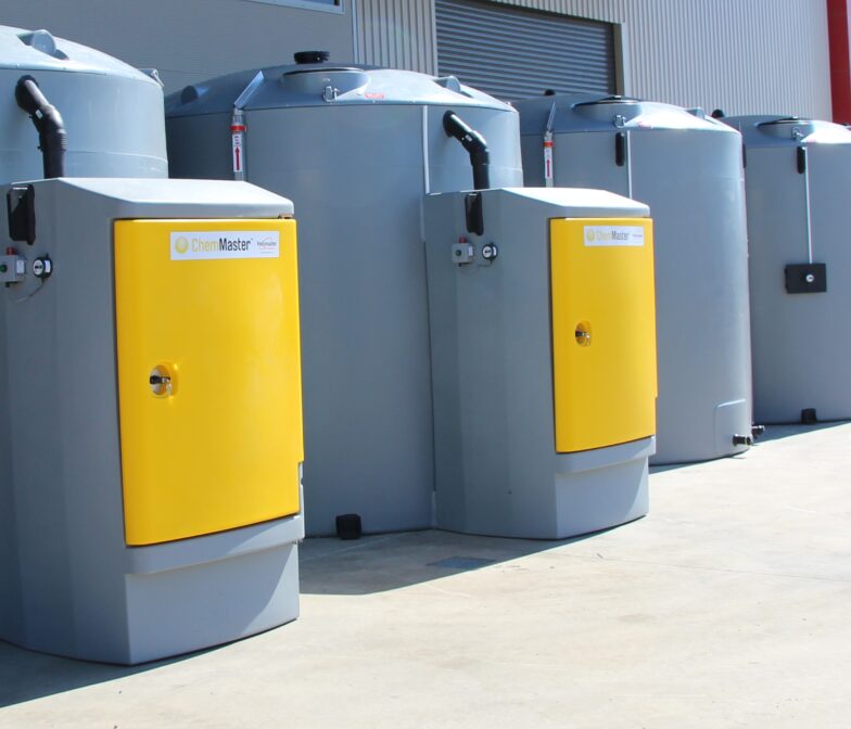 A row of grey and yellow tanks in front of a building.