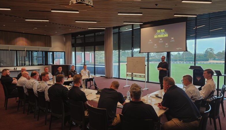 Polymaster team members gathered in a modern conference room during a company training and strategy session with a presenter at a whiteboard and projection screen