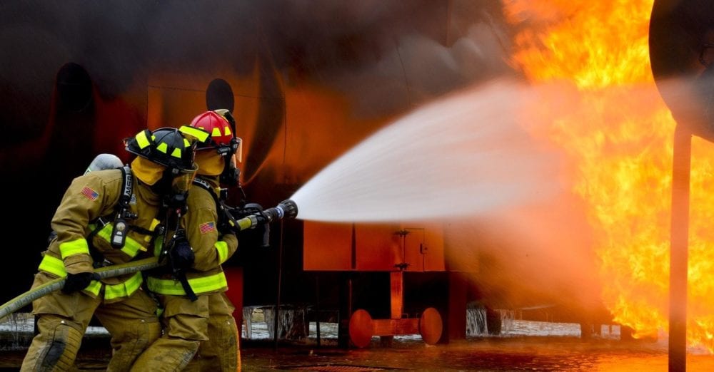 Firefighters splashing water over fire