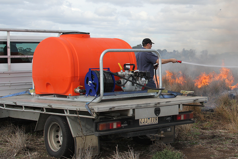 Orange Polymaster FIre-fighting cartage behind a ute vehicle in action