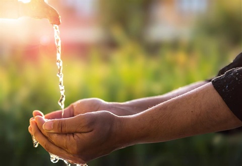 Two hands fetching water from a flowing facuet
