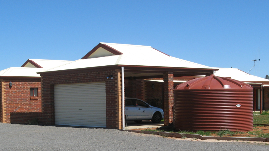 red Polymaster water tank installed beside a residential home