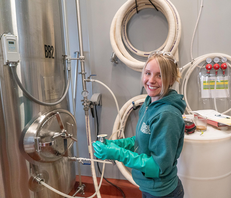 woman wearing pair of teal rubber gloves standing near equipment